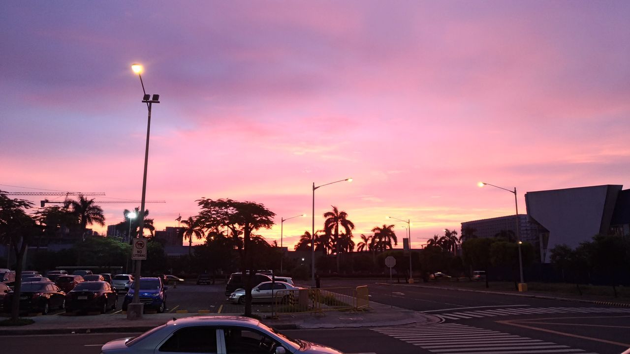 CARS ON ROAD IN CITY AGAINST SUNSET SKY