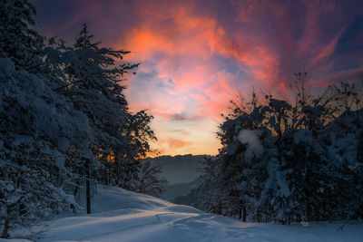 Scenic view of snow covered mountains against sky at sunset