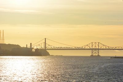 Suspension bridge over river at sunset