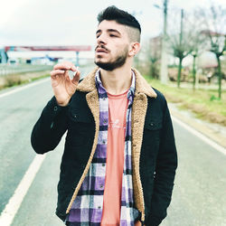 Young man looking away while standing on street