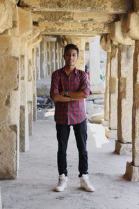 Portrait of young man standing in old corridor