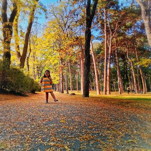 Full length of woman with leaves in park during autumn