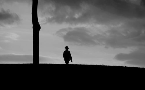 Silhouette man standing on field against sky
