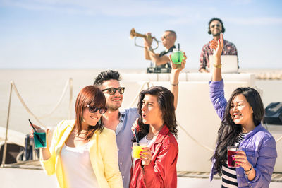 Friends enjoying party at beach against sky