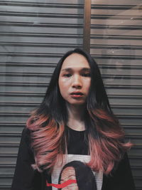 Portrait of young woman standing against wall