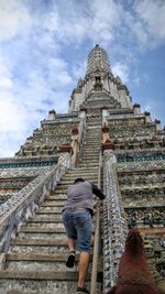 Rear view of man walking on steps at temple