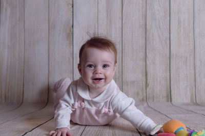 Portrait of cute baby boy on wooden floor