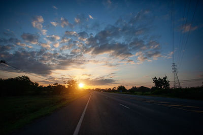 Road amidst trees against sky during sunset