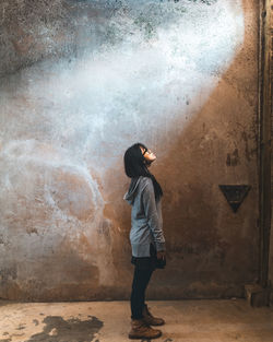 Side view of woman standing against wall