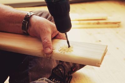 Low section of carpenter drilling on timber