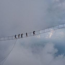 Low angle view of people on fragile bridge