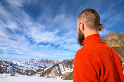 Rear view of man on snowcapped mountain against sky