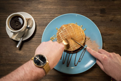 Cropped image of hand holding coffee cup on table