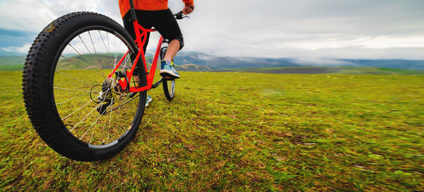 Low section of man riding bicycle on field