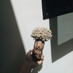 Person holding umbrella against wall