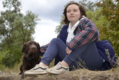 Portrait of woman with dog sitting against plants