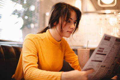 Teenage girl looking at menu while sitting in restaurant