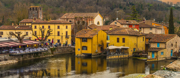 Wide high angle view of borghetto sul mincio with the buildings reflecting on the water at sunset