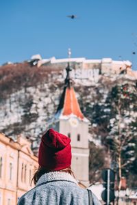 Rear view of woman standing against church during winter