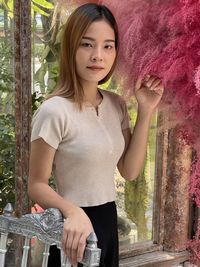 Portrait of woman,beautiful asian girl, stand holding red artificial plant with green leave behind