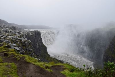 Scenic view of waterfall against sky