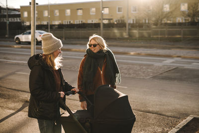 Mothers with baby stroller walking along street