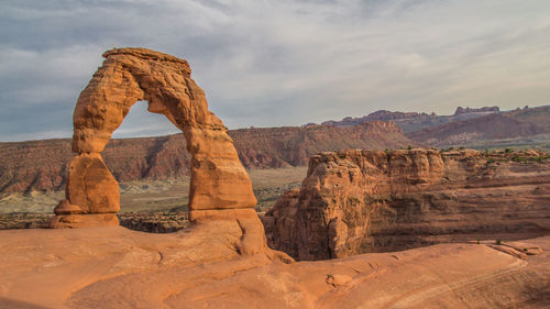 Rock formations on landscape against cloudy sky