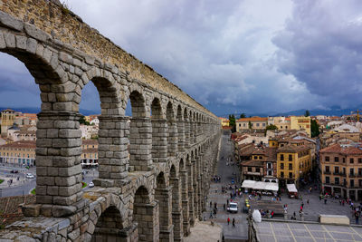 Arch bridge in city against cloudy sky