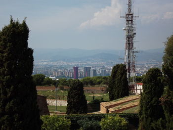 Tower amidst trees and buildings against sky