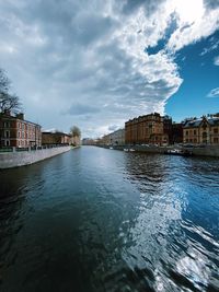 Buildings by river against sky