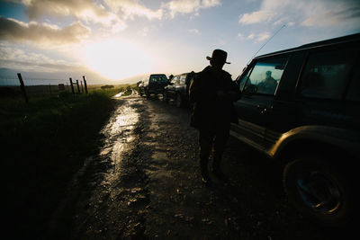 People walking on road against cloudy sky