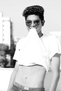 Portrait of young man wearing sunglasses standing against sky