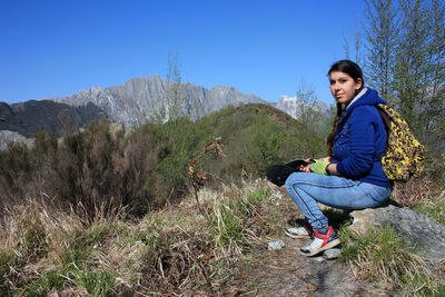 Full length of man sitting on rock against sky