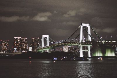 Illuminated bridge over river at night