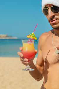 Portrait of shirtless young woman wearing sunglasses at beach