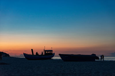 Boat moored on sea against sky during sunset