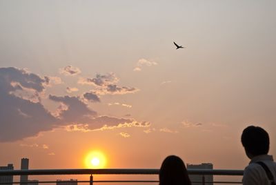 Silhouette of airplane flying against sky during sunset