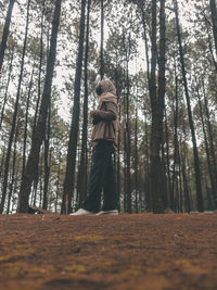 Low angle view of woman amidst trees in forest