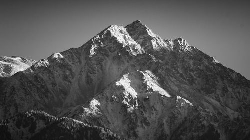 Low angle view of snowcapped mountains against clear sky