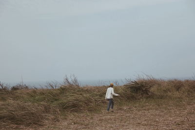 Rear view of man standing on field against clear sky