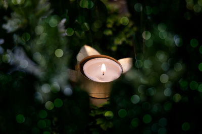 High angle view of illuminated tea light candle with green background