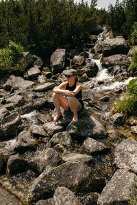 Woman sitting on rock by plants