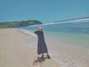 Woman standing on beach by sea against sky