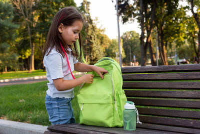 Young girl with backpack and water bottle on park bench