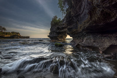 Rock formation on sea shore against sky