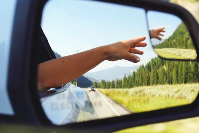 Cropped hand reaching car side-view mirror