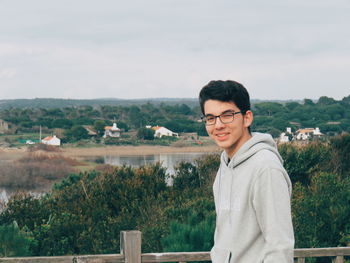 Portrait of young man standing by plants against sky