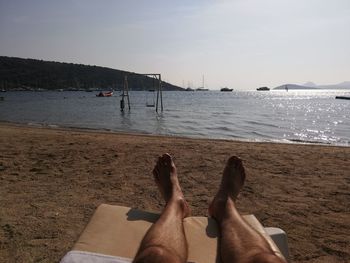 Low section of man relaxing on beach