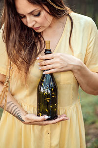 Enchantment, magic, midsummer ritual. woman with fern tattoo holding bottle with lights inside.