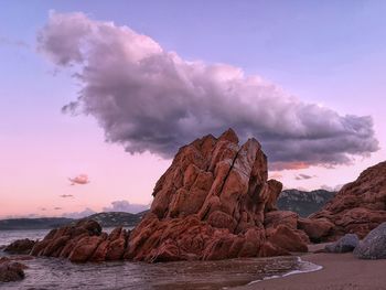 Rock formation on sea shore against sky during sunset